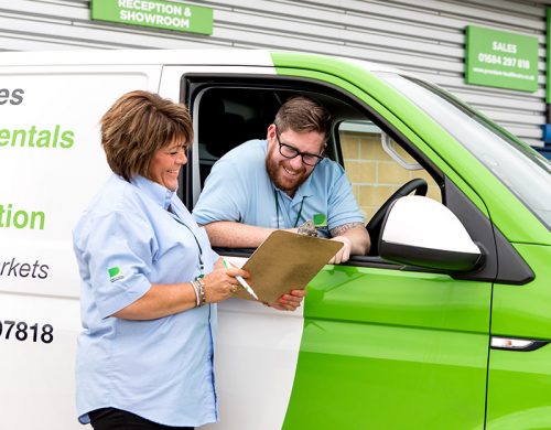 Man in van talking to woman with clip board.