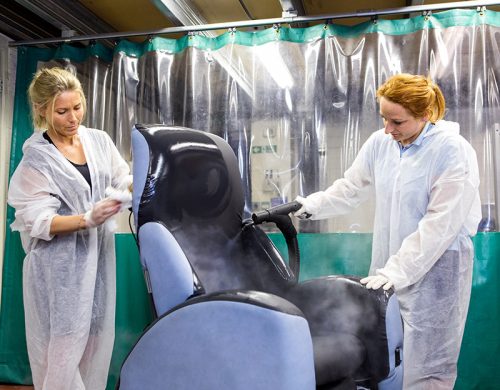 Two people decontaminate chair.