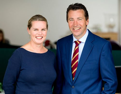 Woman in blue dress standing with man in blue suit.